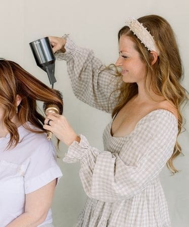 Stylist blow-drying a guest's hair at Hair Expressions